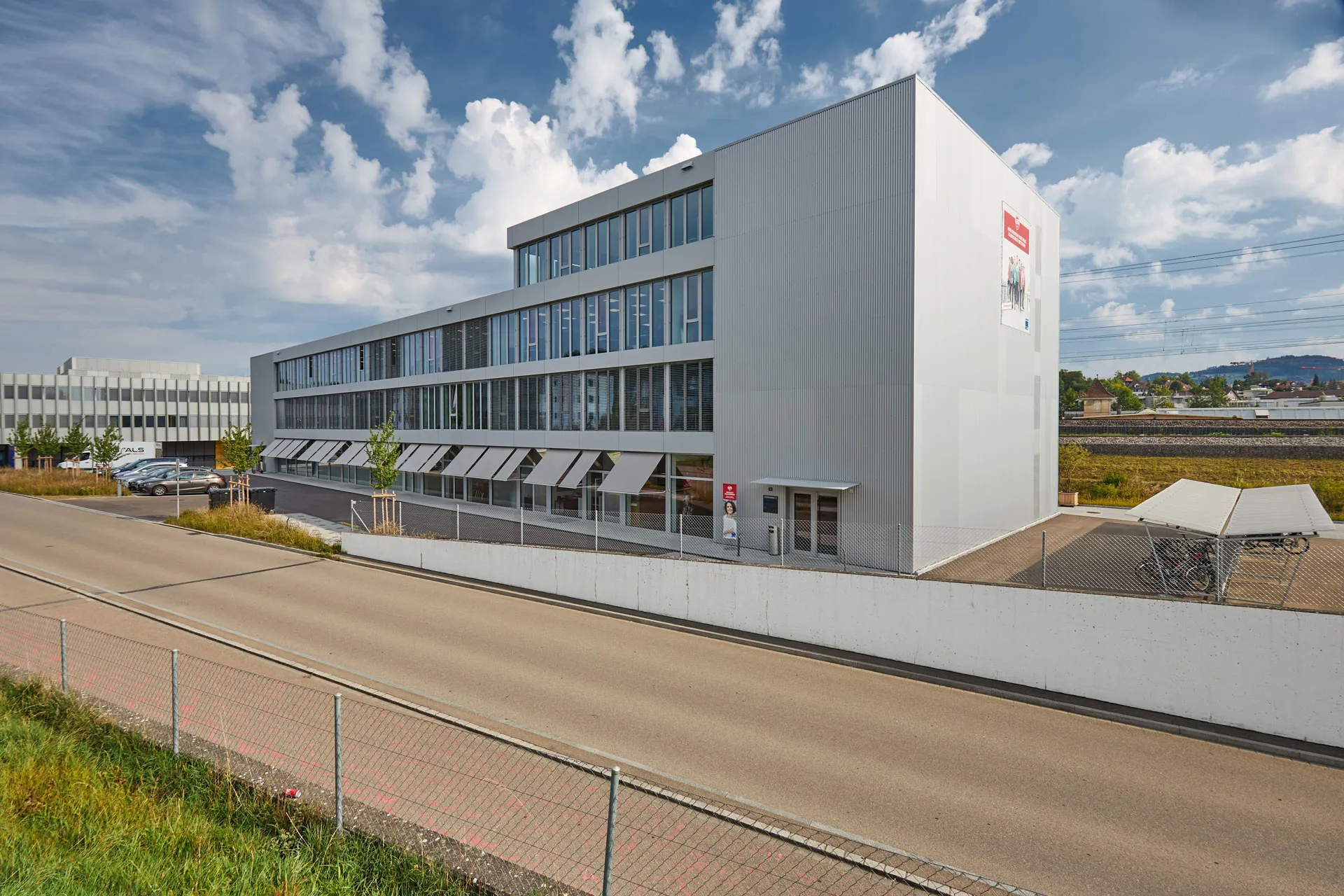 Aussenansicht Gebäude Klubschule Wetzikon mit Strasse und grauer Gebäudefassade